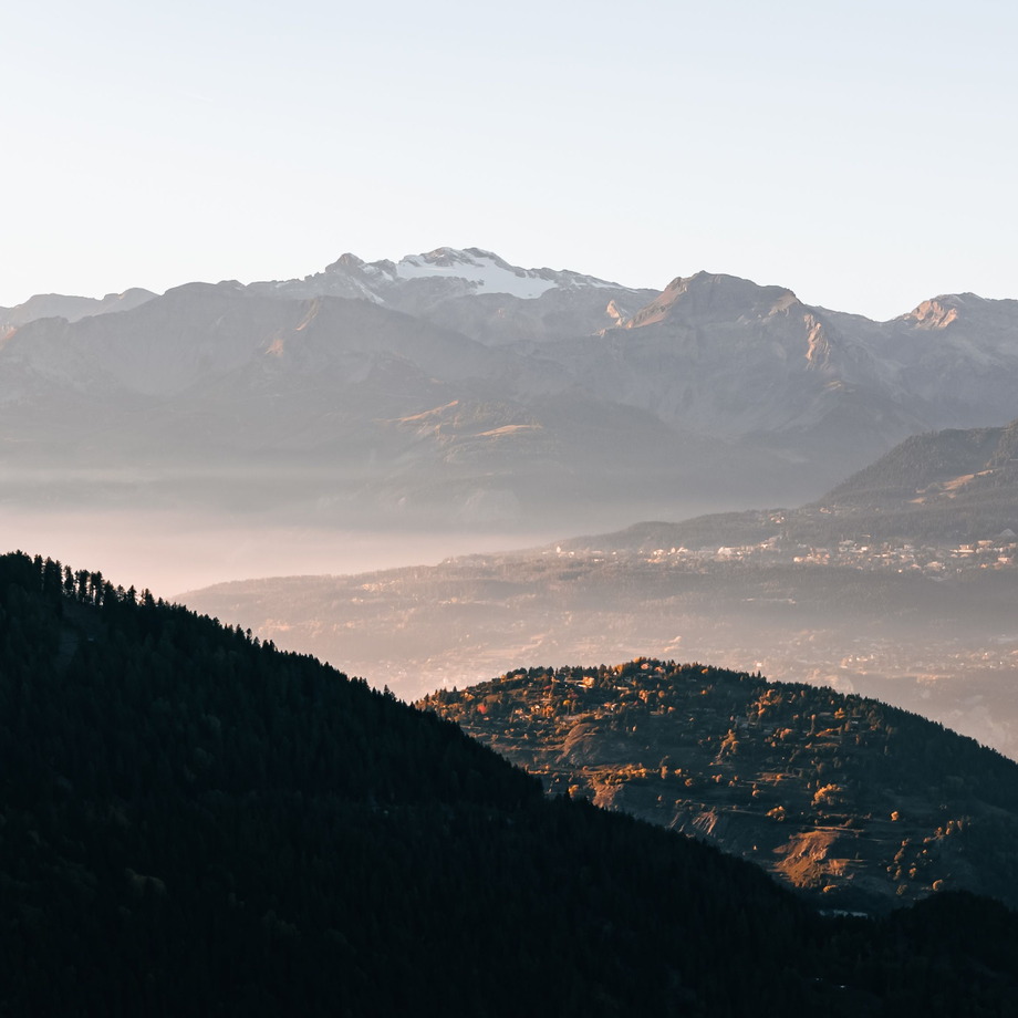 Sommet enneigé des Alpes valaisannes au-dessus d'une vallée dans la brume