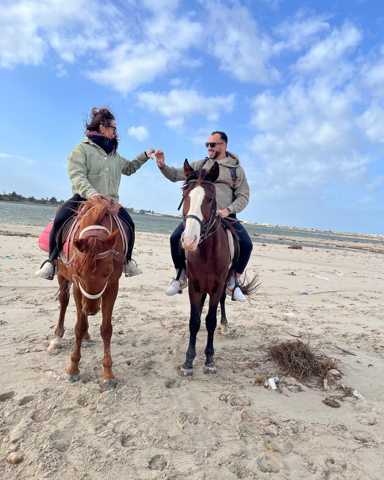 Juan et Emy à cheval sur la plage, au bord de l'eau