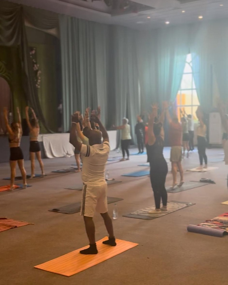 Un cours collectif sur tapis dans la grande salle de l'hôtel, bras levés